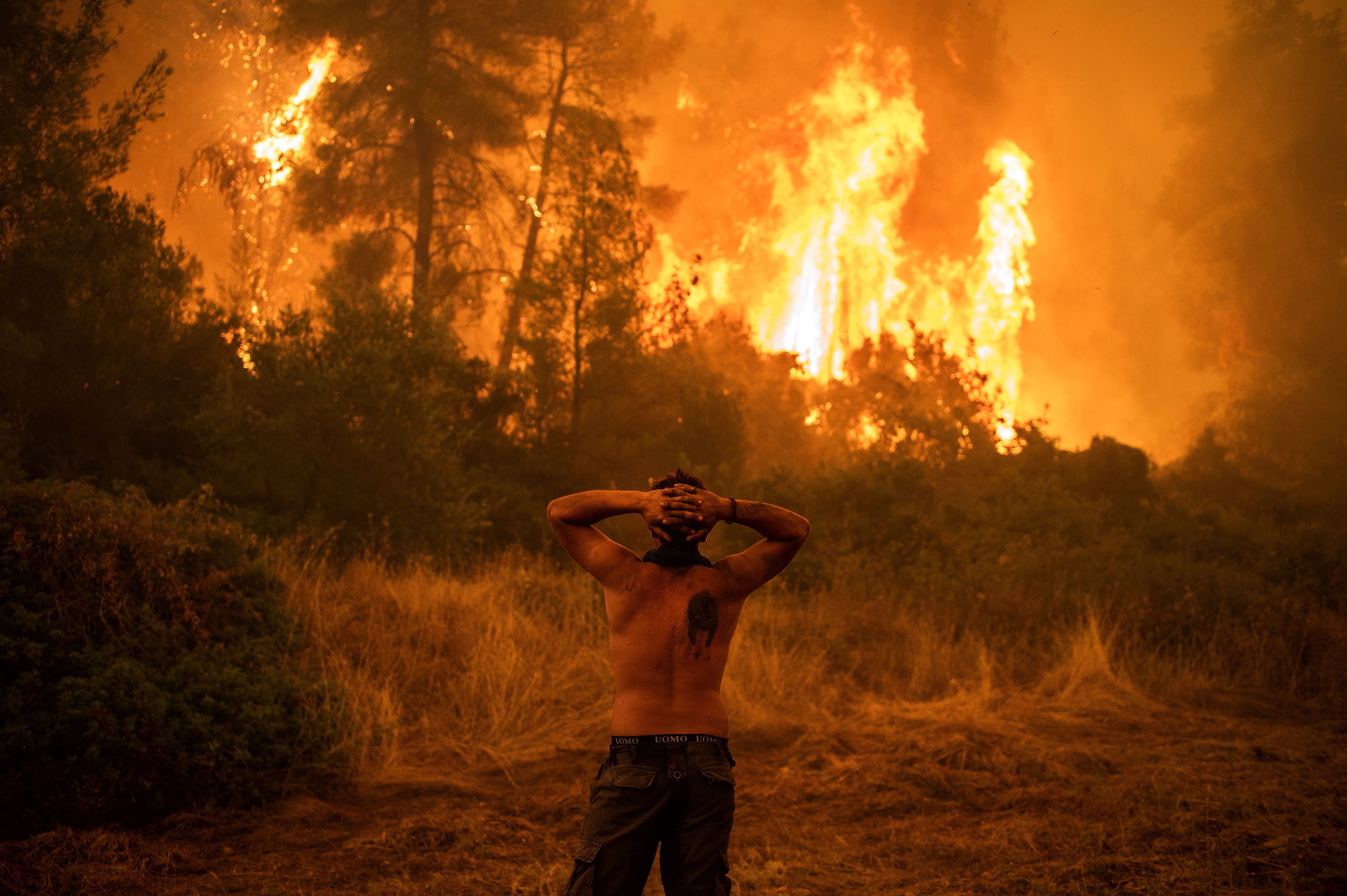 A local resident observes a large blaze approaching the village of Pefki on Evia island, Greece's second largest island, on 8 August, 2021.