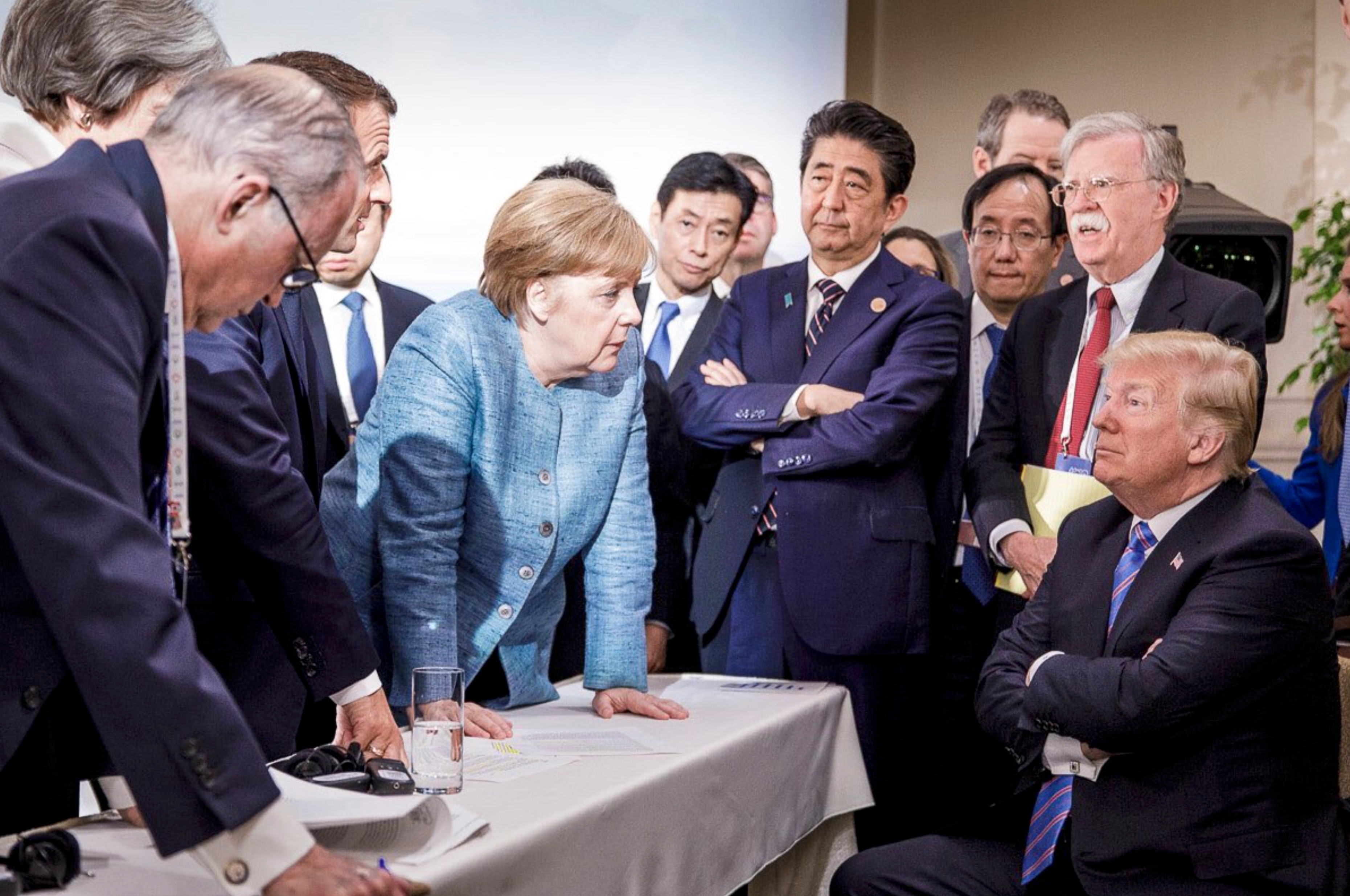 A symbolic photo of the 2018 G7 meeting shows German Chancellor Angela Merkel looking down on US President Donald Trump.