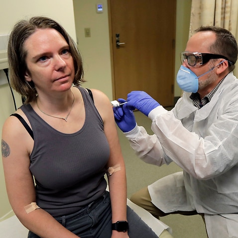 A woman in the US is given the first shot in the clinical trial of a potential vaccine for the COVID-19 coronavirus by a pharmacist.