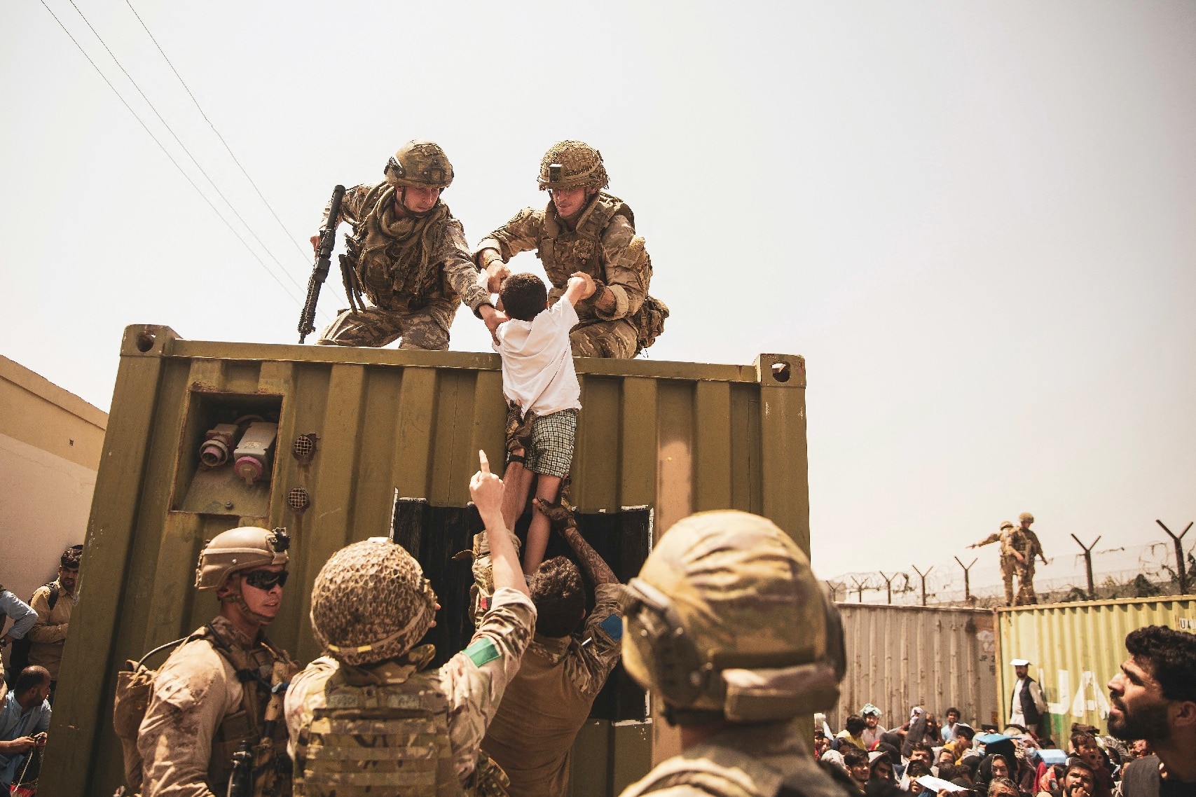 UK coalition forces, Turkish coalition forces, and US Marines assist a child during an evacuation at Hamid Karzai International Airport on 20 August 2021.