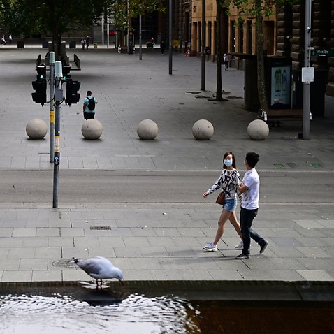 A couple walk through a near empty Martin Place in Sydney, Monday, 13 April, 2020. 