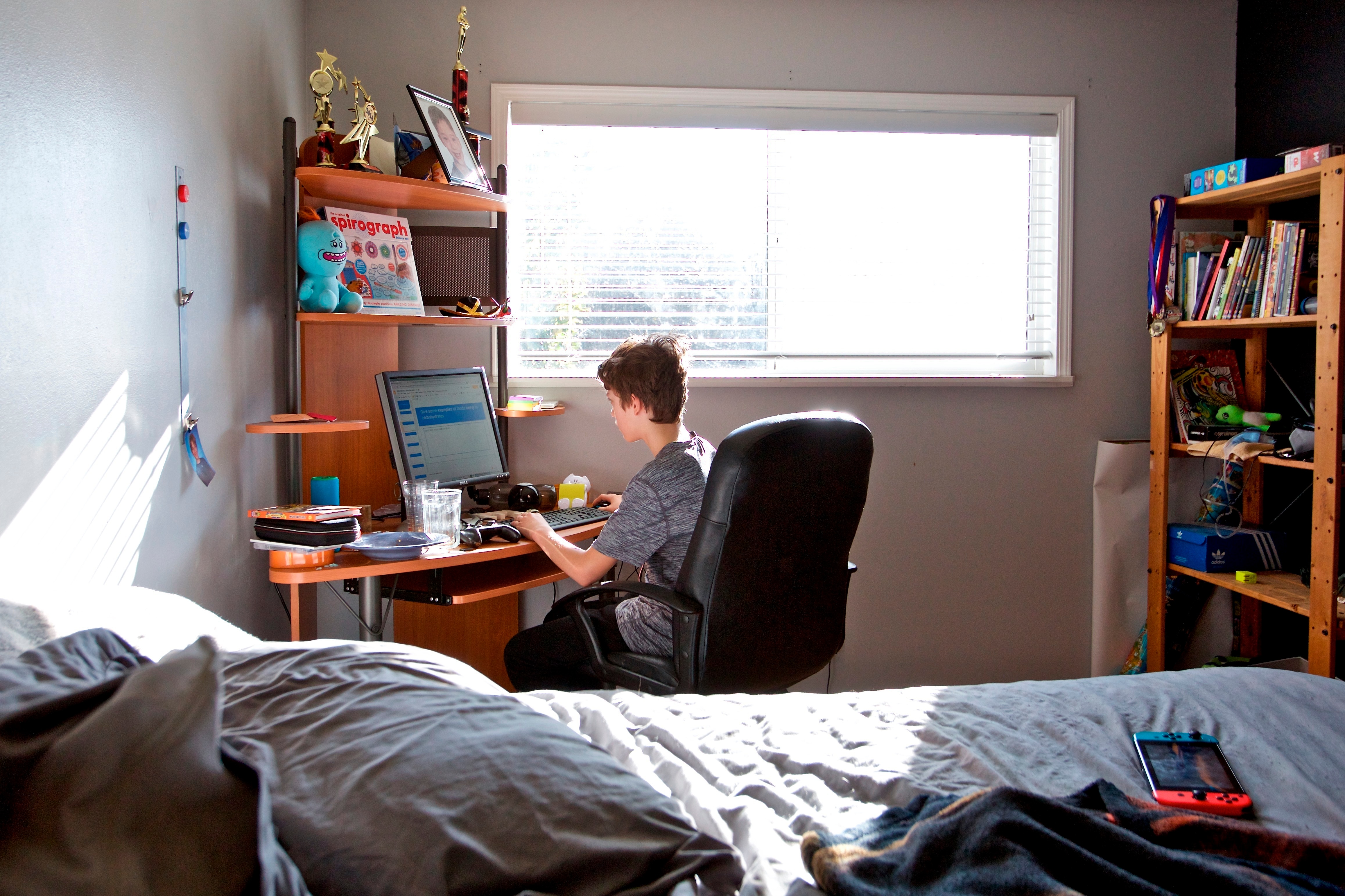 يعمل الطالب في مهمة دراسية عبر الإنترنت في غرفة نومه.