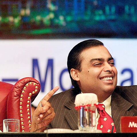 Chairman of Reliance Industries, Dhirubhai H. Ambani (L), points towards a share holder while his son and vice chairman, Mukesh Ambani (R), laughs in Bombay, 08 April 2002 at an extraordinary general meeting. 