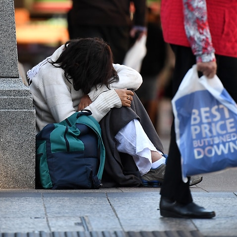 A woman sits on a street corner in central Brisbane