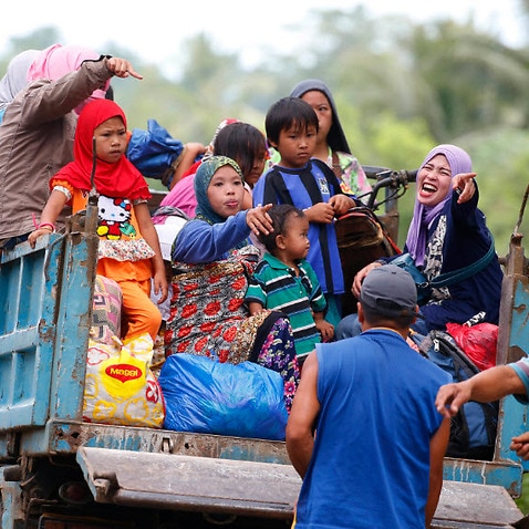 Displaced residents fleeing by a truck to safer areas stop by a roadside as government troops battle with Muslim militants 