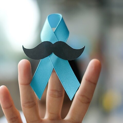Cropped Image Of Hand Holding Blue Ribbon With Mustache