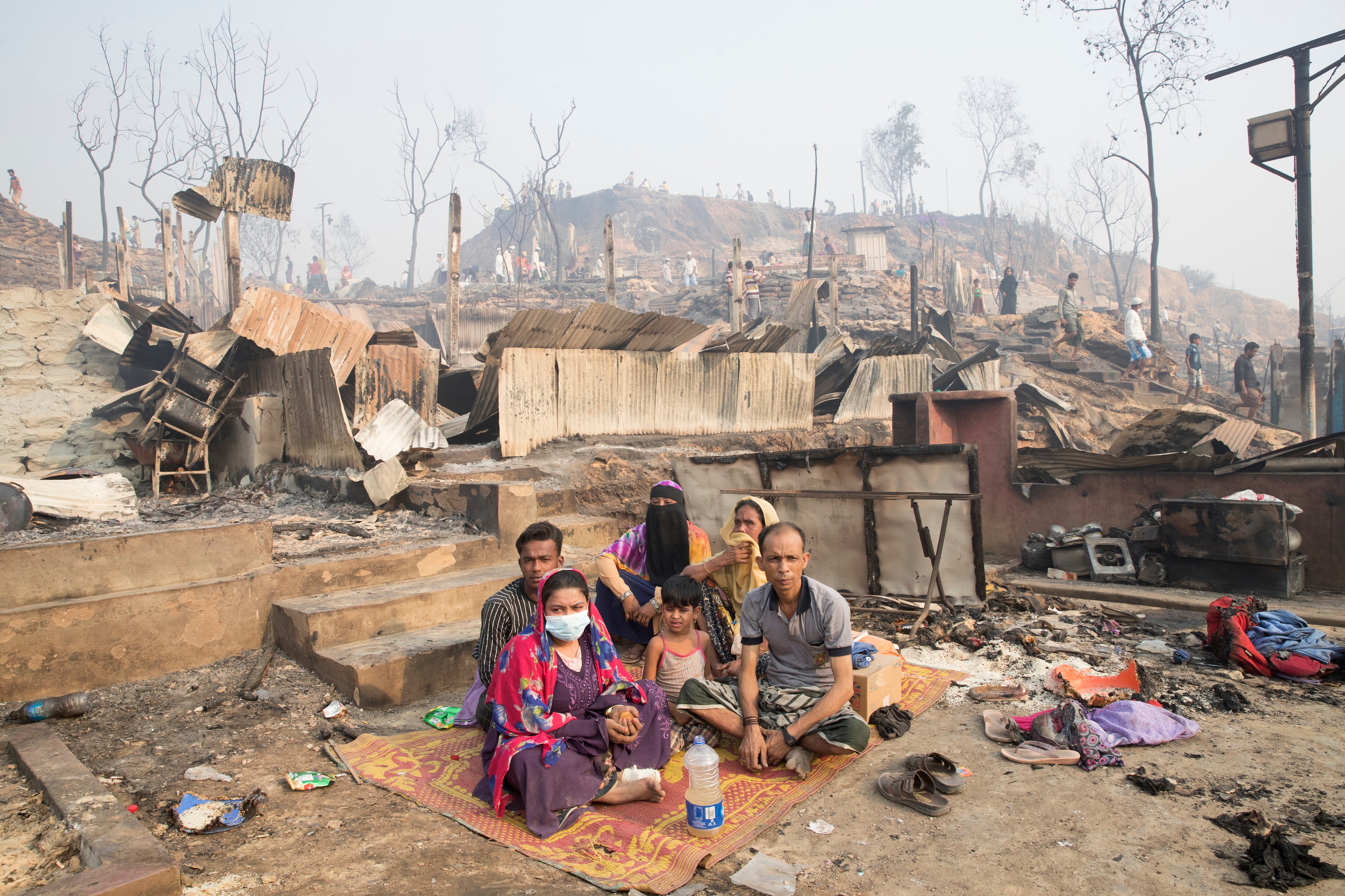 A Rohingya family sits under an open sky after a huge fire swept through a Rohingya refugee camp in southern Bangladesh on Monday.