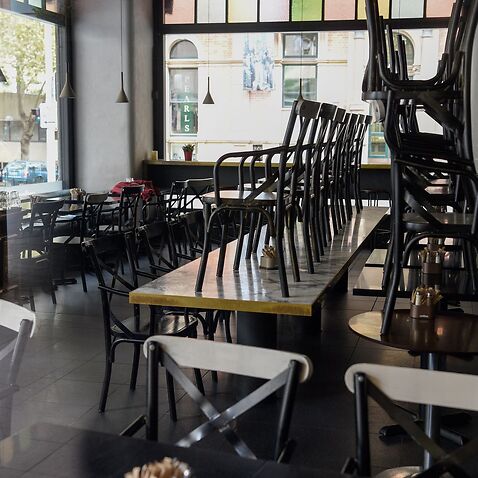 Stacked tables and chairs are seen in a closed Sydney cafe