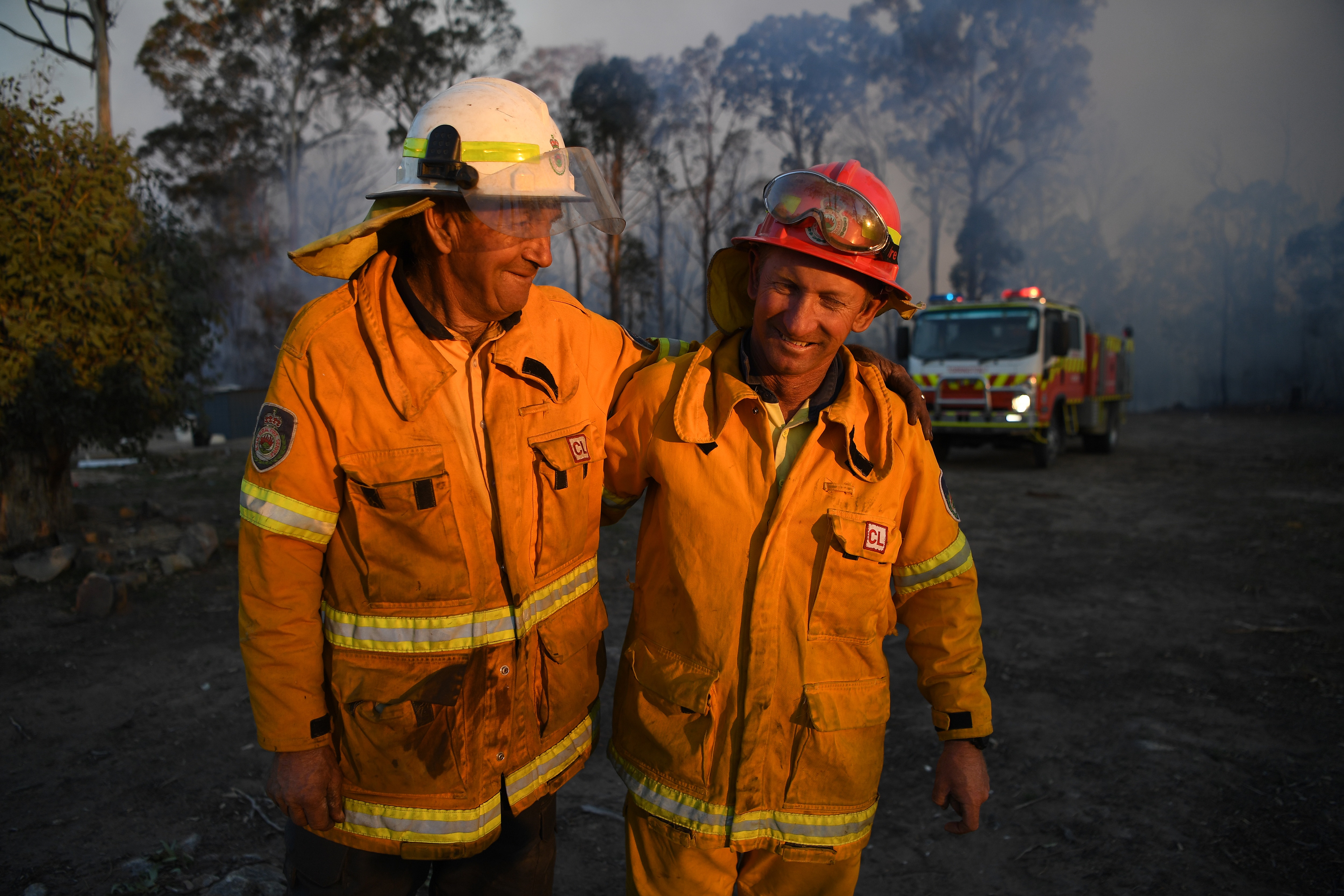 NSW Rural Fire Service volunteers Bob (left) and Greg Kneipp, a father and son, embrace after successfully defending a property in Torrington, near Glen Innes.