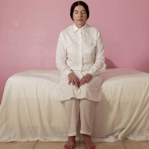 Artist Marina Abramovic sitting on a bed