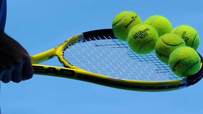 A man holds tennis balls on a tennis racquet at Melbourne Park