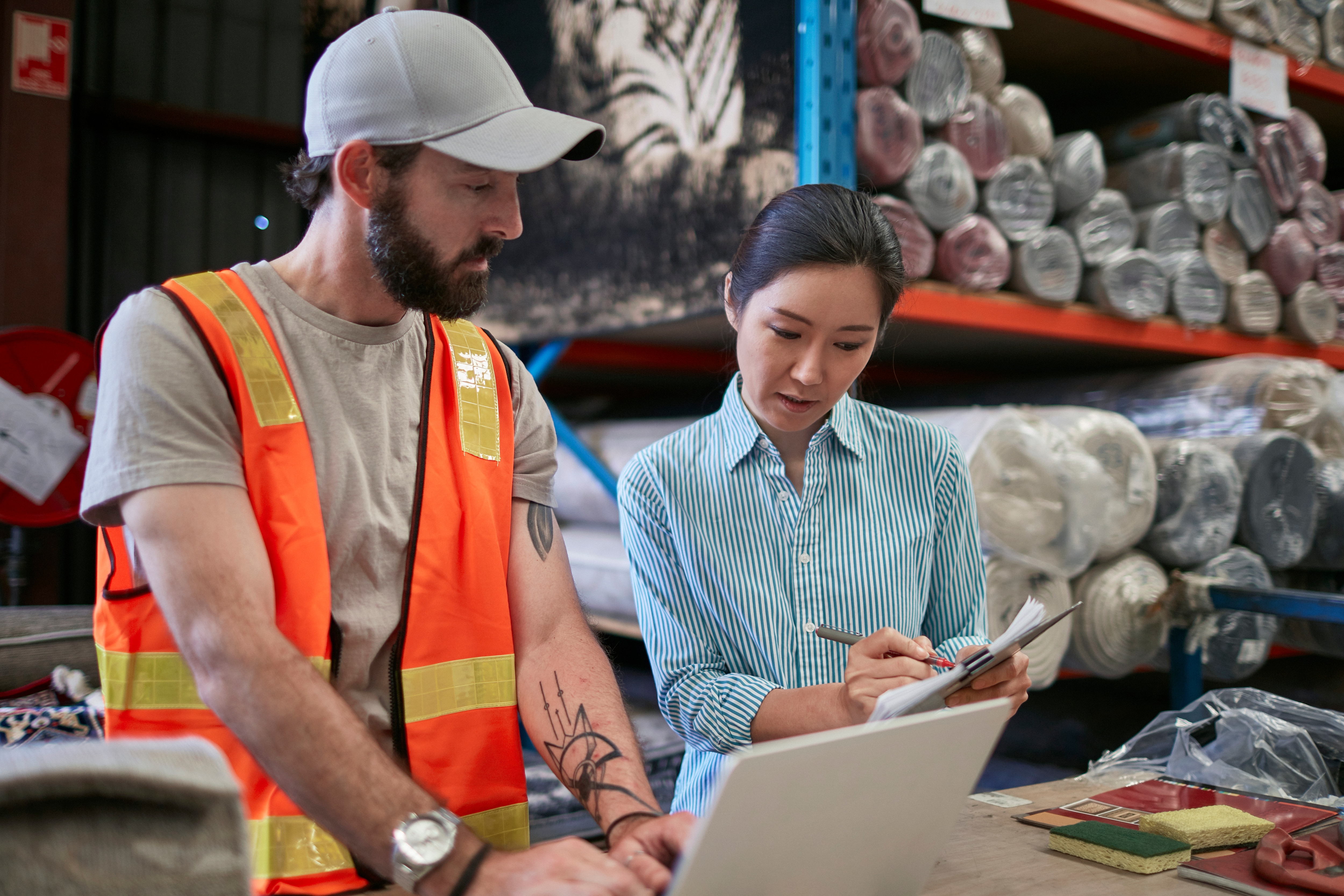 Workers with clipboard and laptop in rug warehouse