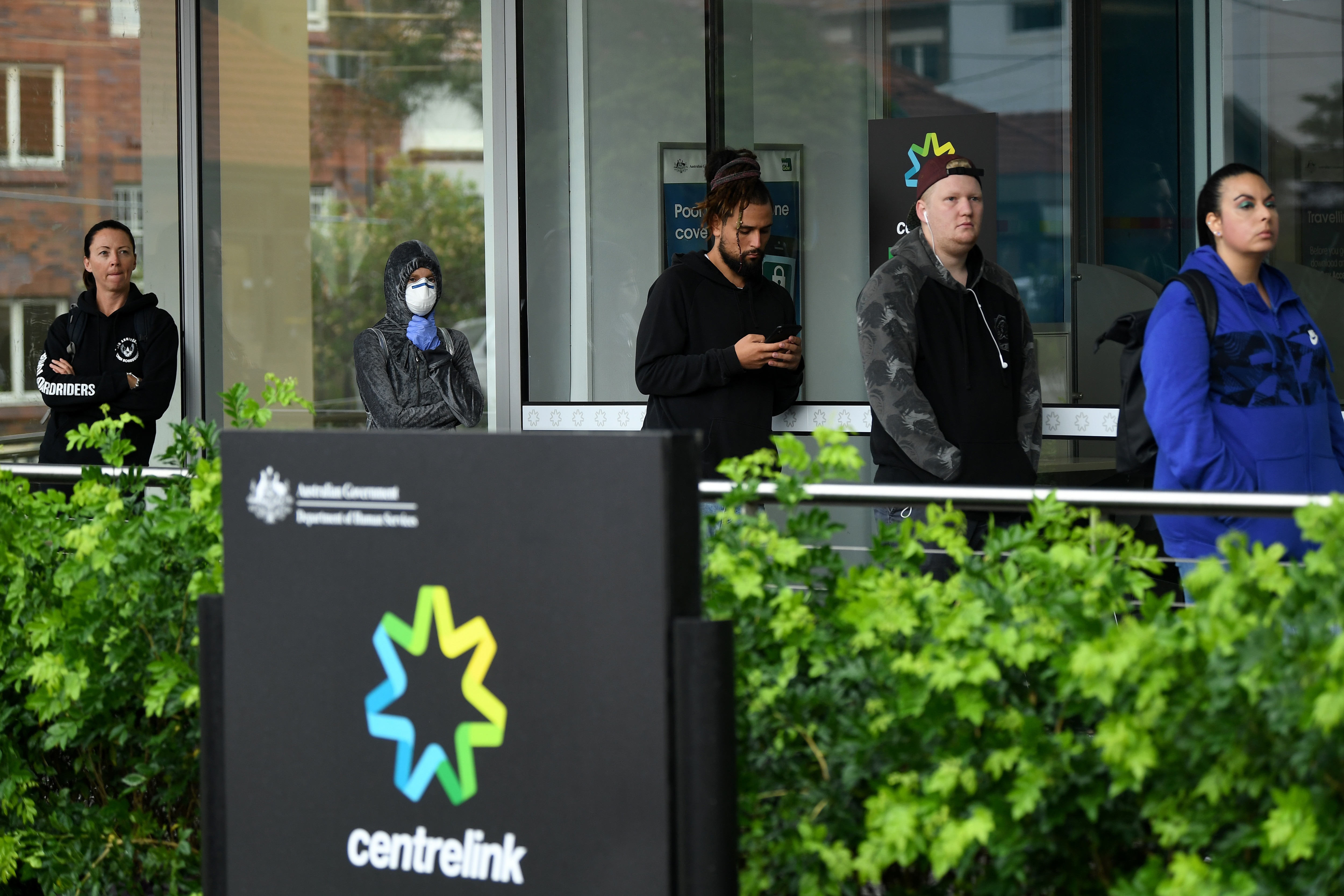 People are seen queuing outside a Centrelink office in Bondi Junction, Sydney.