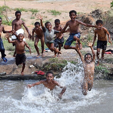 This picture taken on November 19, 2018 show children jumping in a small pond to beat the heat on the outskirts of Port Moresby. (Photo by SAEED KHAN / AFP)        (Photo credit should read SAEED KHAN/AFP via Getty Images)