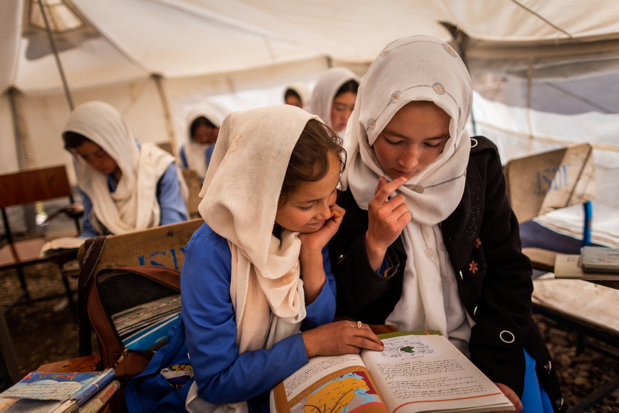 Students sharing a textbook in class in one of the overflow tents at the school.