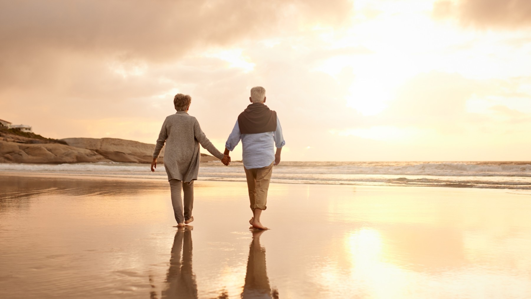 Older couple holding hands on beach 