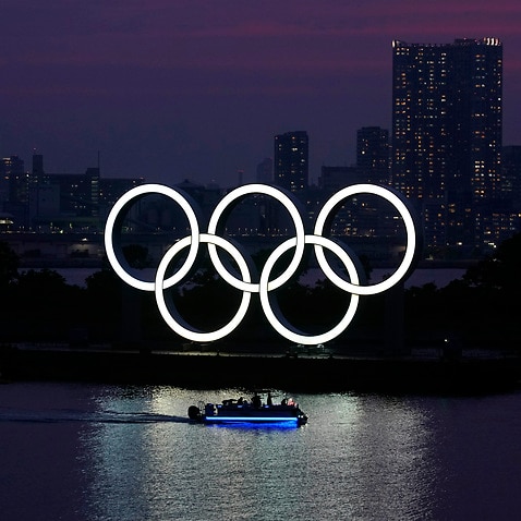 The Olympic rings float in the water at sunset in Tokyo.