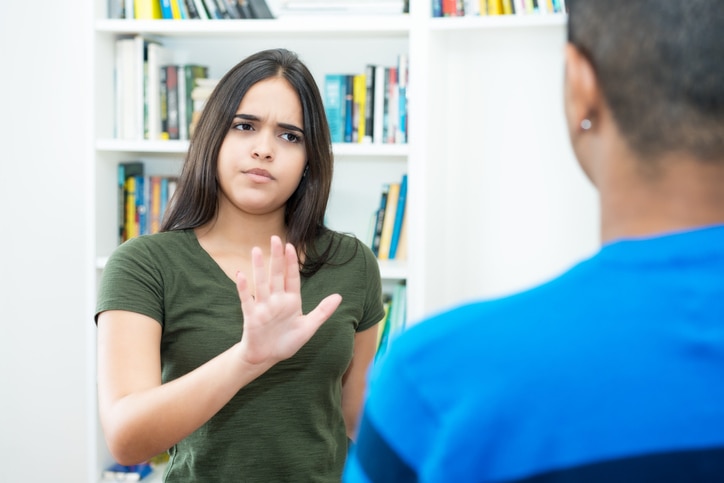 Hispanic female young adult gesturing stop and social distancing