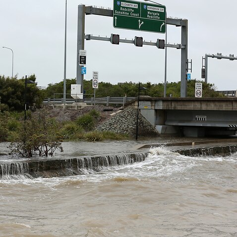 A fisherman is seen near a flooded bike path beneath the Ted Smout Memorial Bridge during wet weather over Morton Bay, Monday, 14 December, 2020. 
