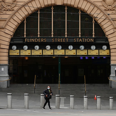 A person is seen crossing a quiet Flinders Street in Melbourne, Monday, July 19, 2021.  (AAP Image/Daniel Pockett) NO ARCHIVING                                  