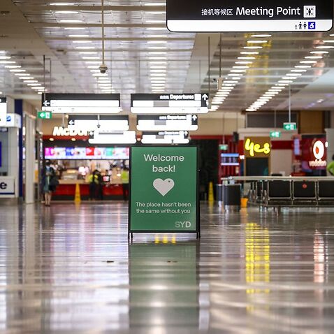 A sign is displayed inside the empty arrivals hall at the international airport in Sydney on 15 October, 2021. 