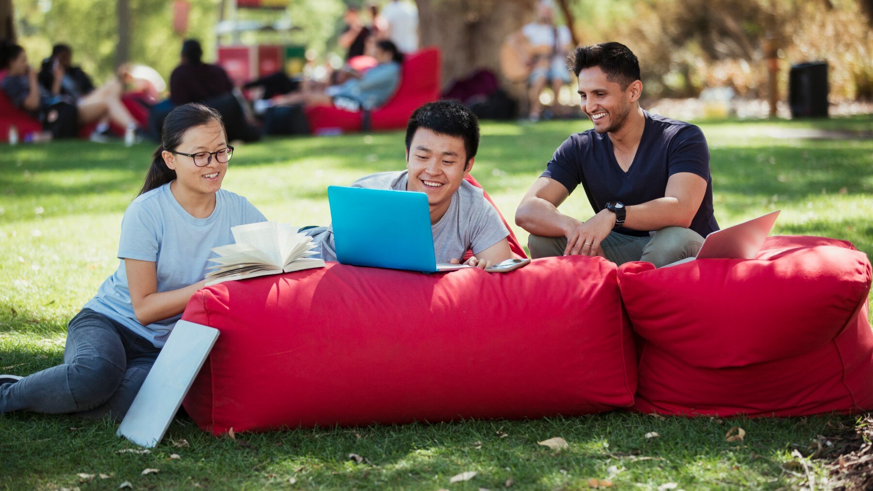 A group of multi ethnic students sitting together on bean bags outdoors on a sunny day in Perth.