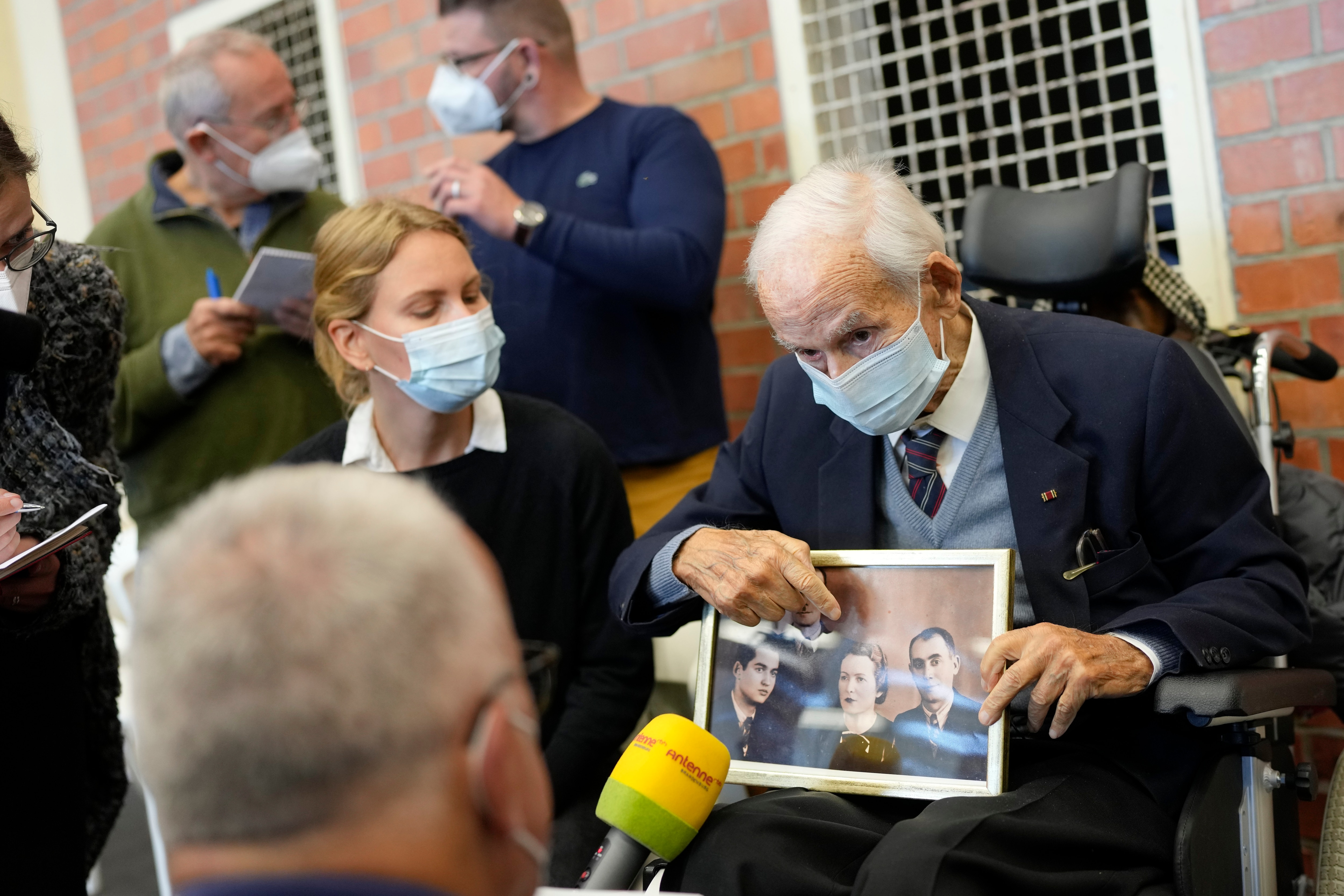 Leon Schwarzbaum, a 100-year-old Holocaust survivor, shows a family photo as he speaks to media ahead of the trial of a former concentration camp guard.