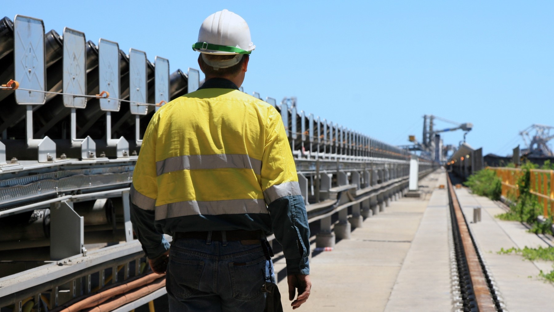 Worker in uniform beside a coal conveyer belt 