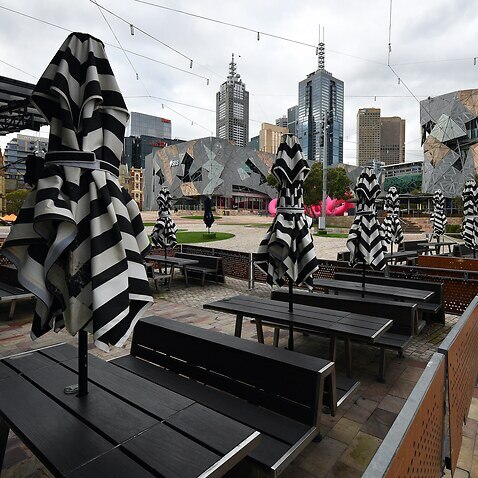 Empty tables are seen at a closed restaurant in Federation Square, Melbourne.
