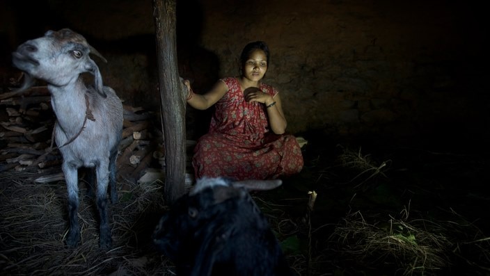 Laxmi Tamatta, aged 20, sits in a 'Chaupadi' shed in Biraltoli village in Acham district, Nepal. Laxmi got married at the age of