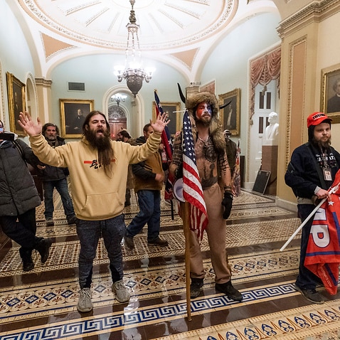 Jake Angeli (centre) - known online as the ‘Q Shaman’ - pictured inside the Capitol.