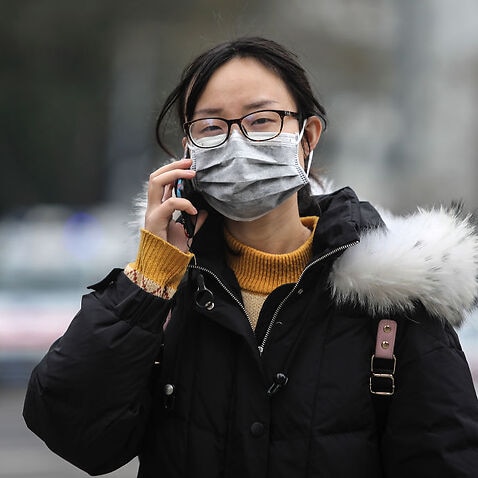 A woman wears a mask outside the closed Huanan Seafood Wholesale Market, January 17, 2020 in Wuhan, Hubei province, China