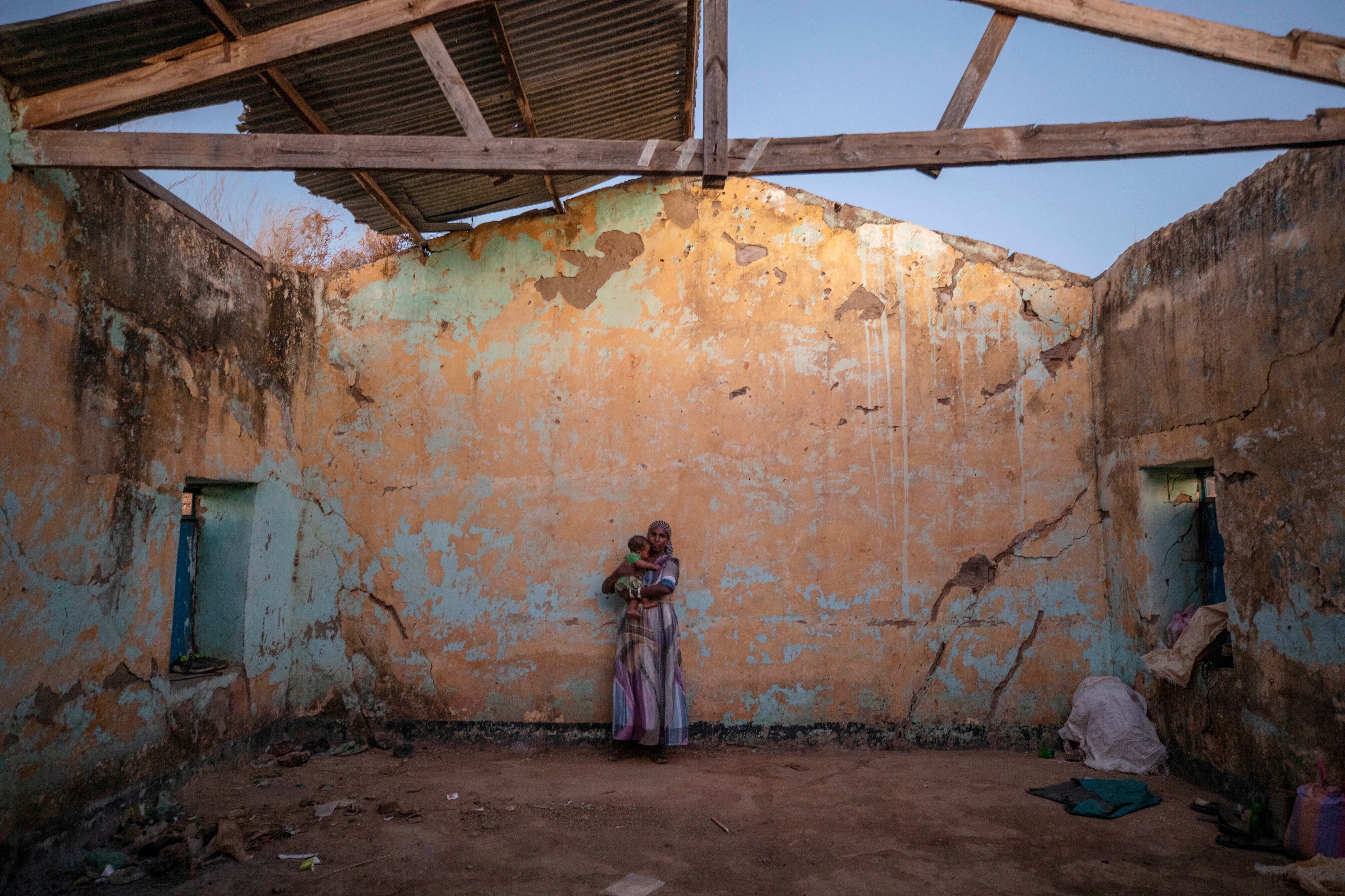 A Tigray woman who fled the conflict in Ethiopia's Tigray region holds her child inside temporary shelter at Umm Rakouba refugee camp in Qadarif, eastern Sudan