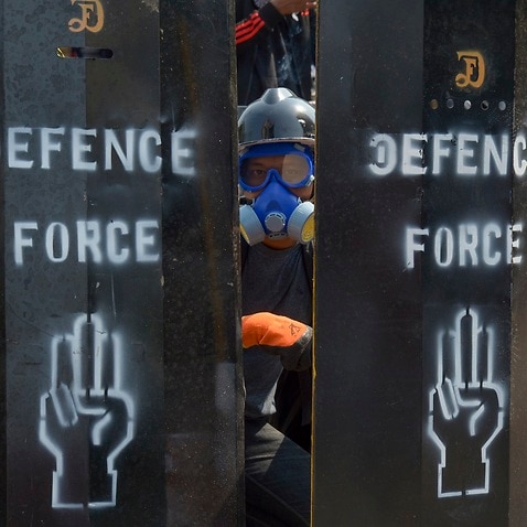 An anti-coup protester stands behind a makeshift barricade in Yangon, Myanmar.