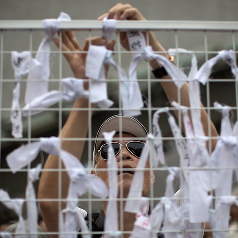An elderly man ties ribbons with messages of support for young protesters during a rally in Hong Kong.