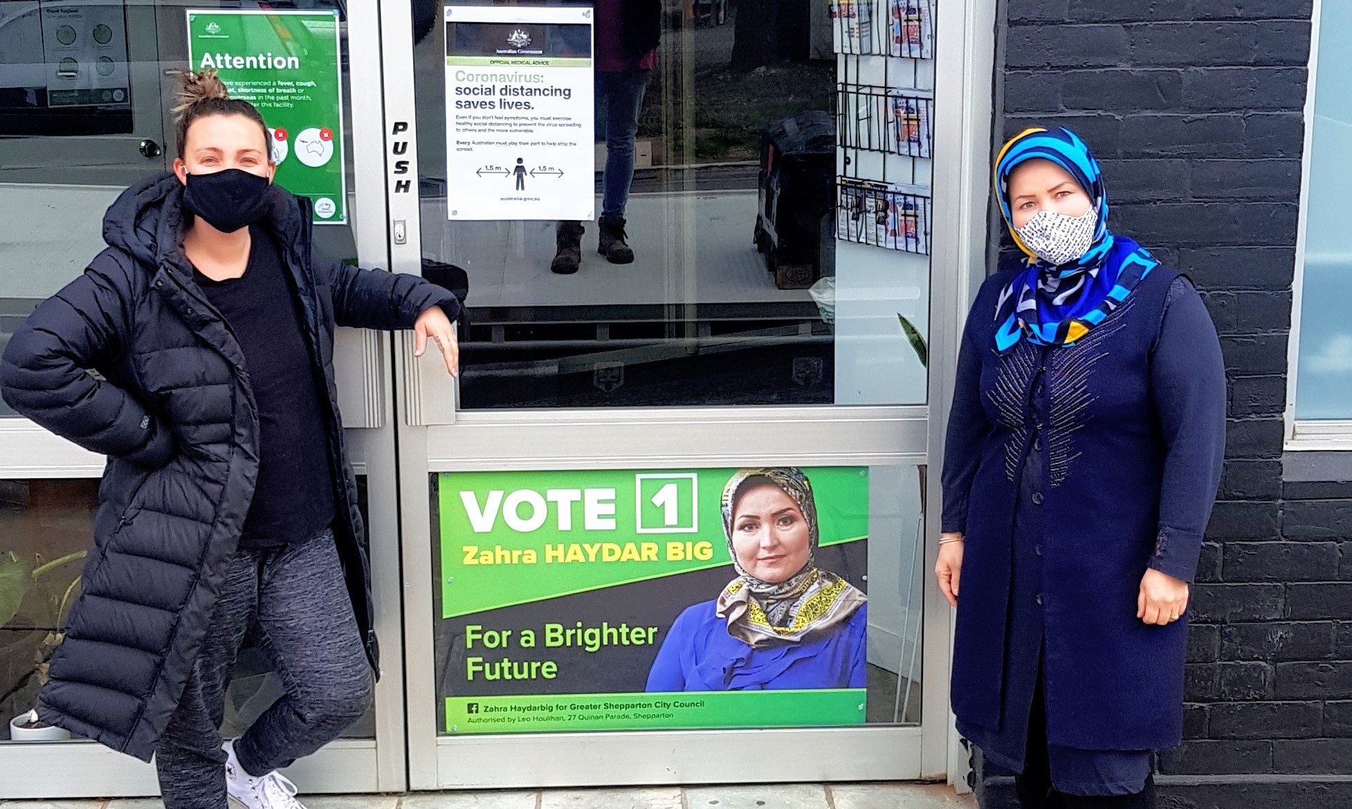 Zahra Haydarbig (right) and the Creative Director of Greater Shepparton Festivals Jamie Lea posing next to her election campaign poster.
