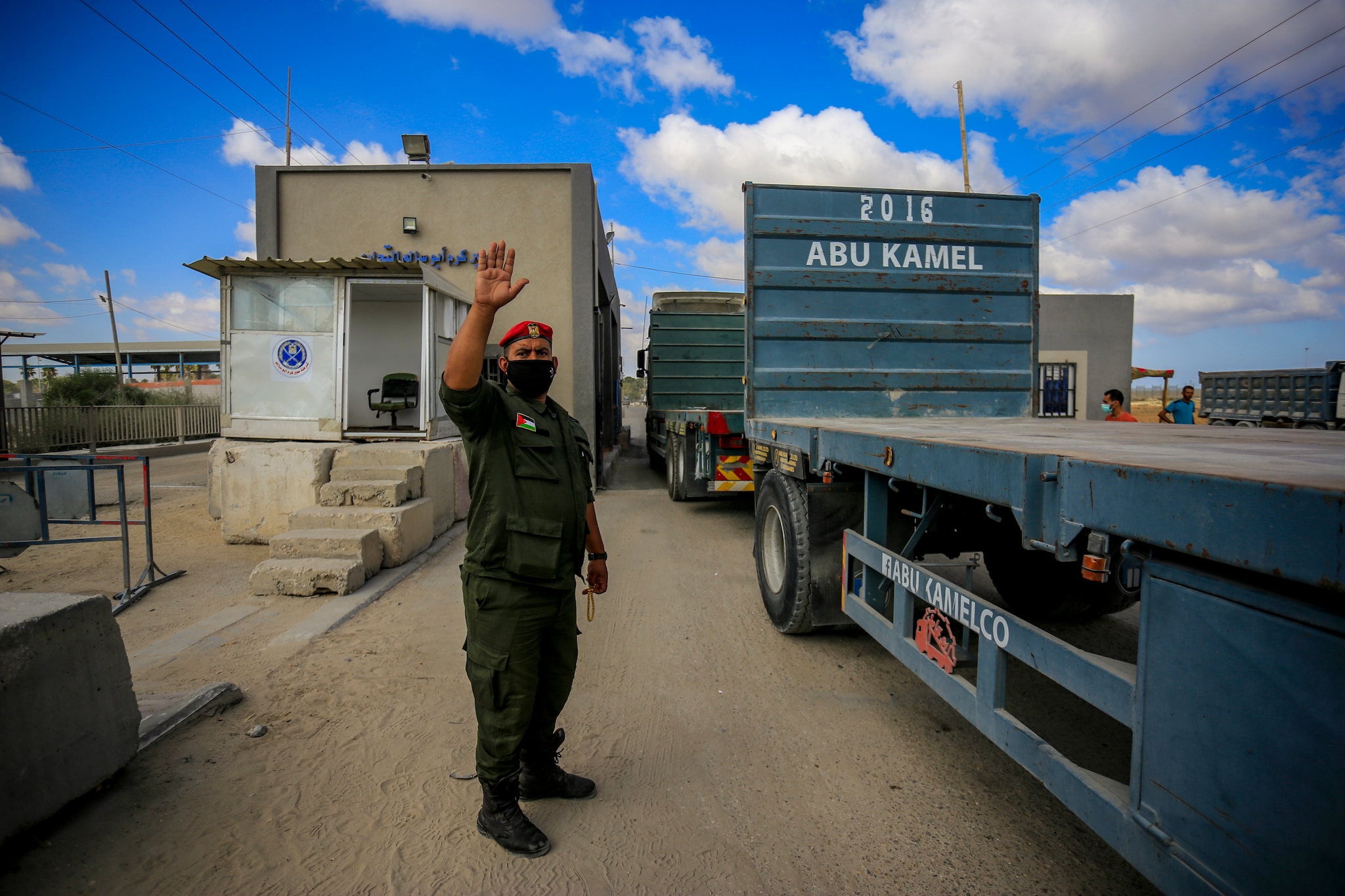 A member of Palestinian Hamas security forces guides trucks entering the Kerem Shalom crossing.