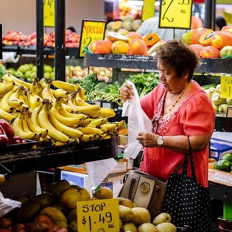 A older shopper looks at the fruit on display in a supermarket.