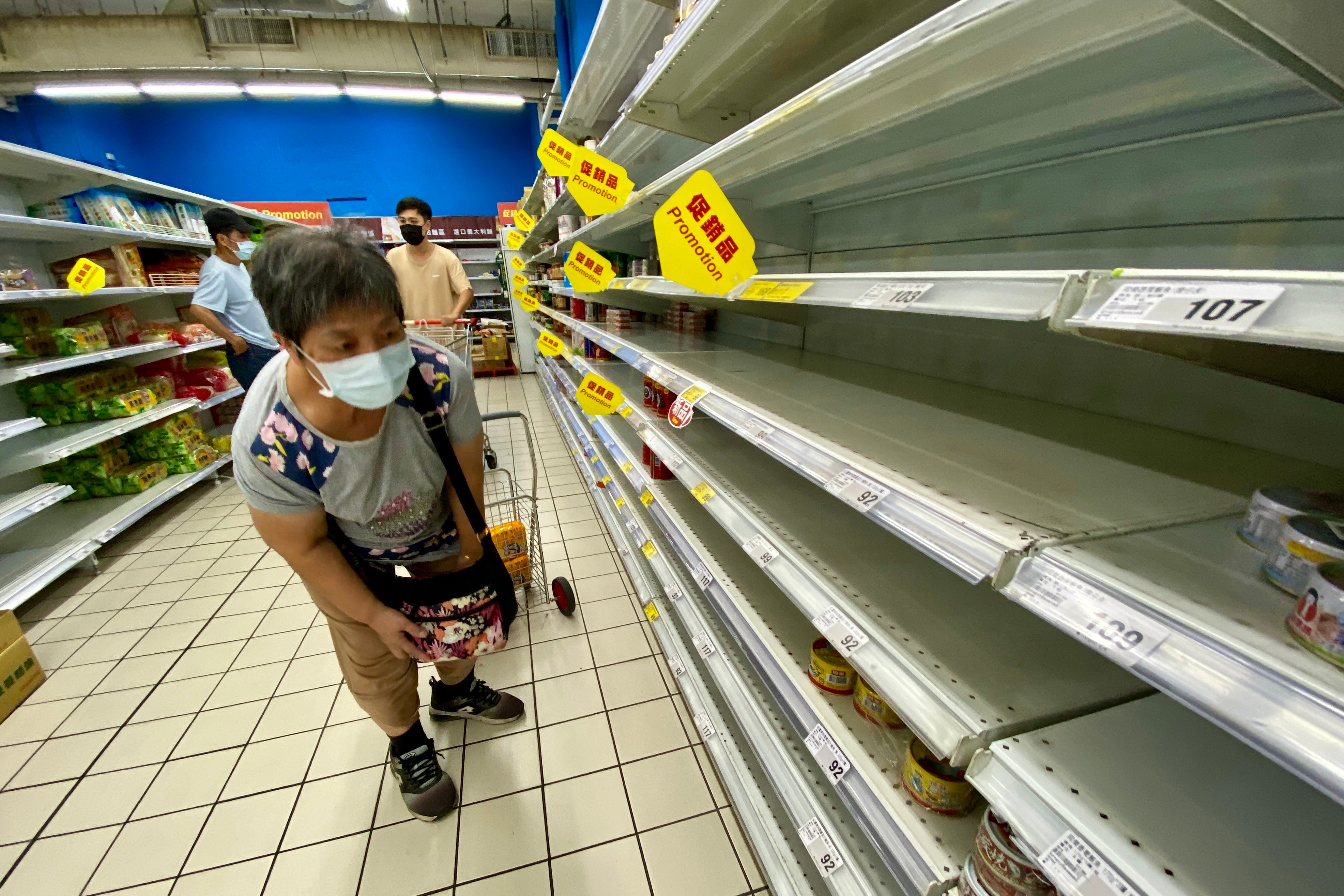 A woman checks an almost empty shelf as residents rushed to buy grocery essentials inside a supermarket in Taipei, Taiwan, 17 May 2021. 