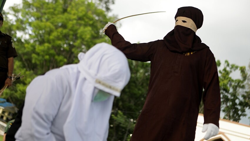 A sharia executioner, known as algojo, during a public caning punishment in Jantho, Aceh Besar Regency, Indonesia, in 2017.