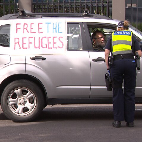 Police question a protester outside the Mantra Hotel in Melbourne. 