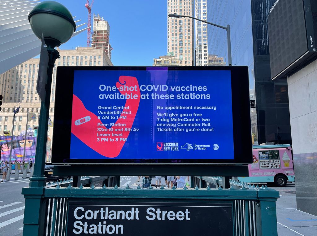 A poster advertising rewards such as metro cards for COVID-19 vaccination is seen above the entrance to a subway station in New York City.