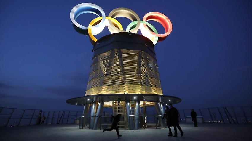 Visitors walk near the lit-up Olympic rings atop of the Olympic Tower in Beijing, China.