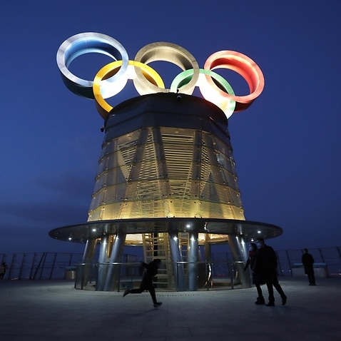 Visitors walk near the lit-up Olympic rings atop of the Olympic Tower in Beijing, China.