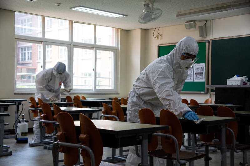 Health officials spray disinfectant in a classroom of the Yeongdongil High School in Seoul, South Korea, 11 May 2020