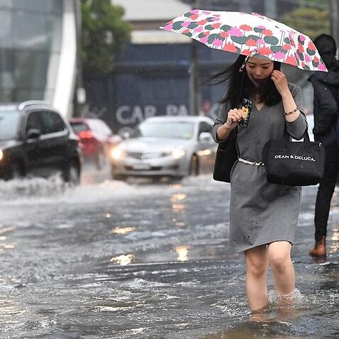 Pedestrians walk through flood waters in South Melbourne.