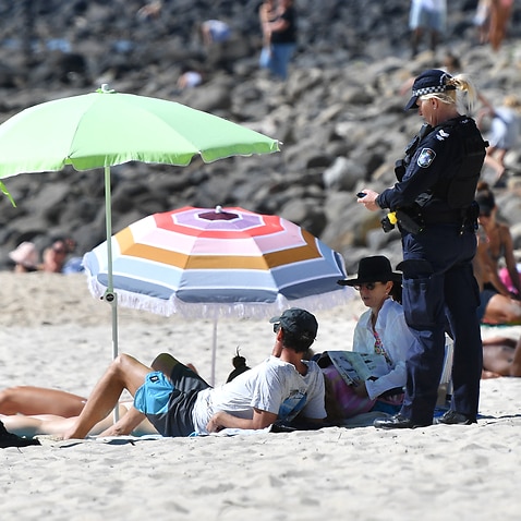 A police officer speaks to beachgoers at Burleigh Heads on Queensland's Gold Coast.