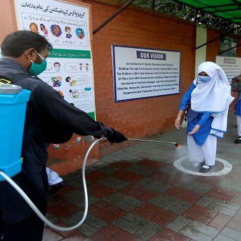A worker disinfects the shoes of a student as she arrives at school in Lahore, Pakistan