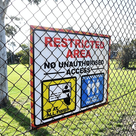 Signage is seen along the perimeter fence of the Melbourne Immigration Transit Accommodation complex in Broadmeadows, Melbourne.