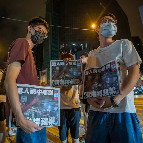 Supporters hold copies of the final edition of the Apply Daily newspaper early on 24 June.